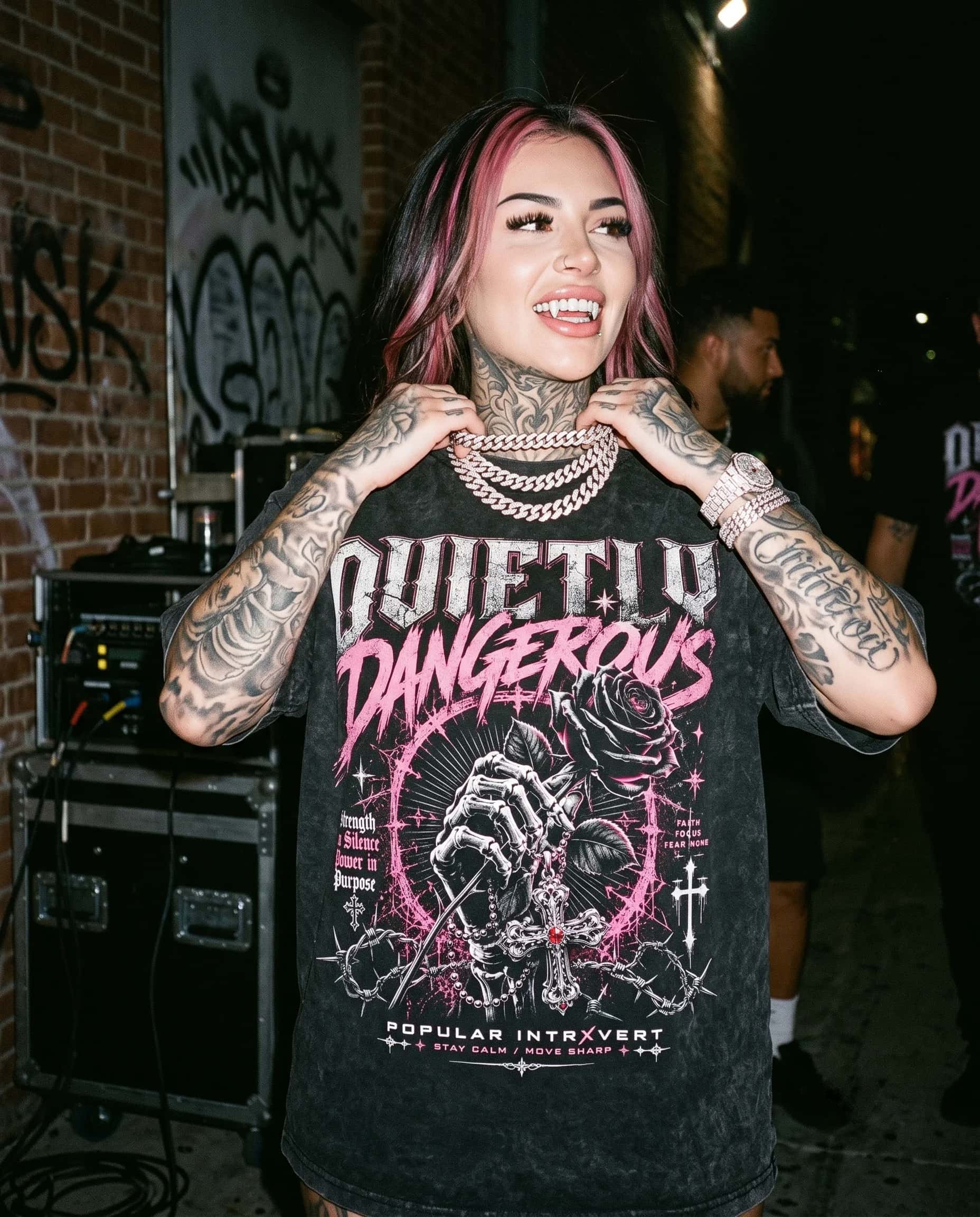 Woman wearing the Popular Intrxvert Quietly Dangerous graphic tee on a city street at night